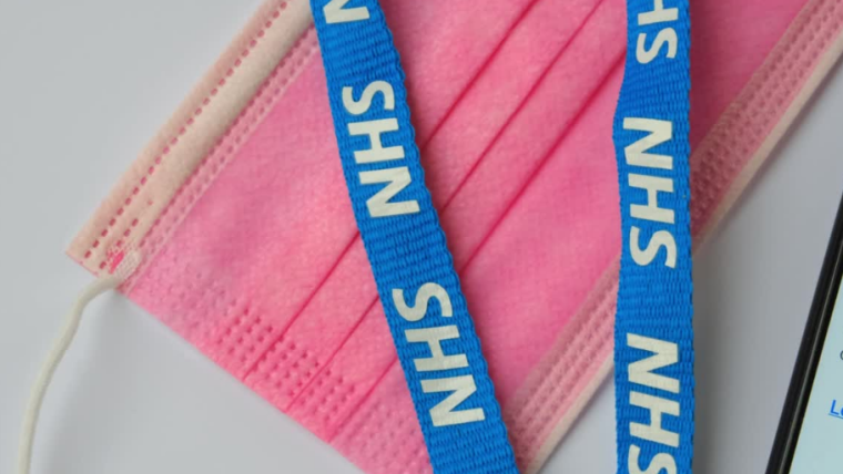 Image of pink disposable face mask and blue NHS lanyard
